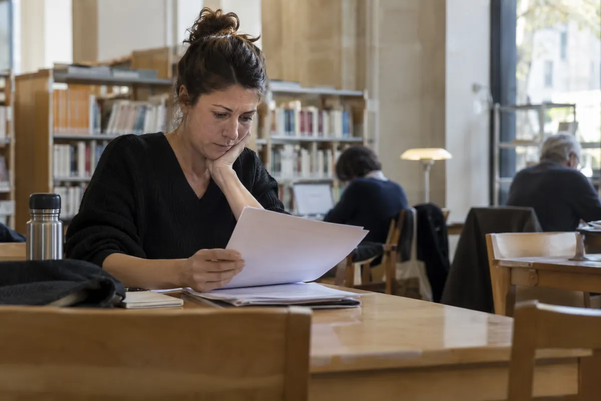 Lectrice comparant ses documents à la bibliothèque — image d’ambiance générée par IA