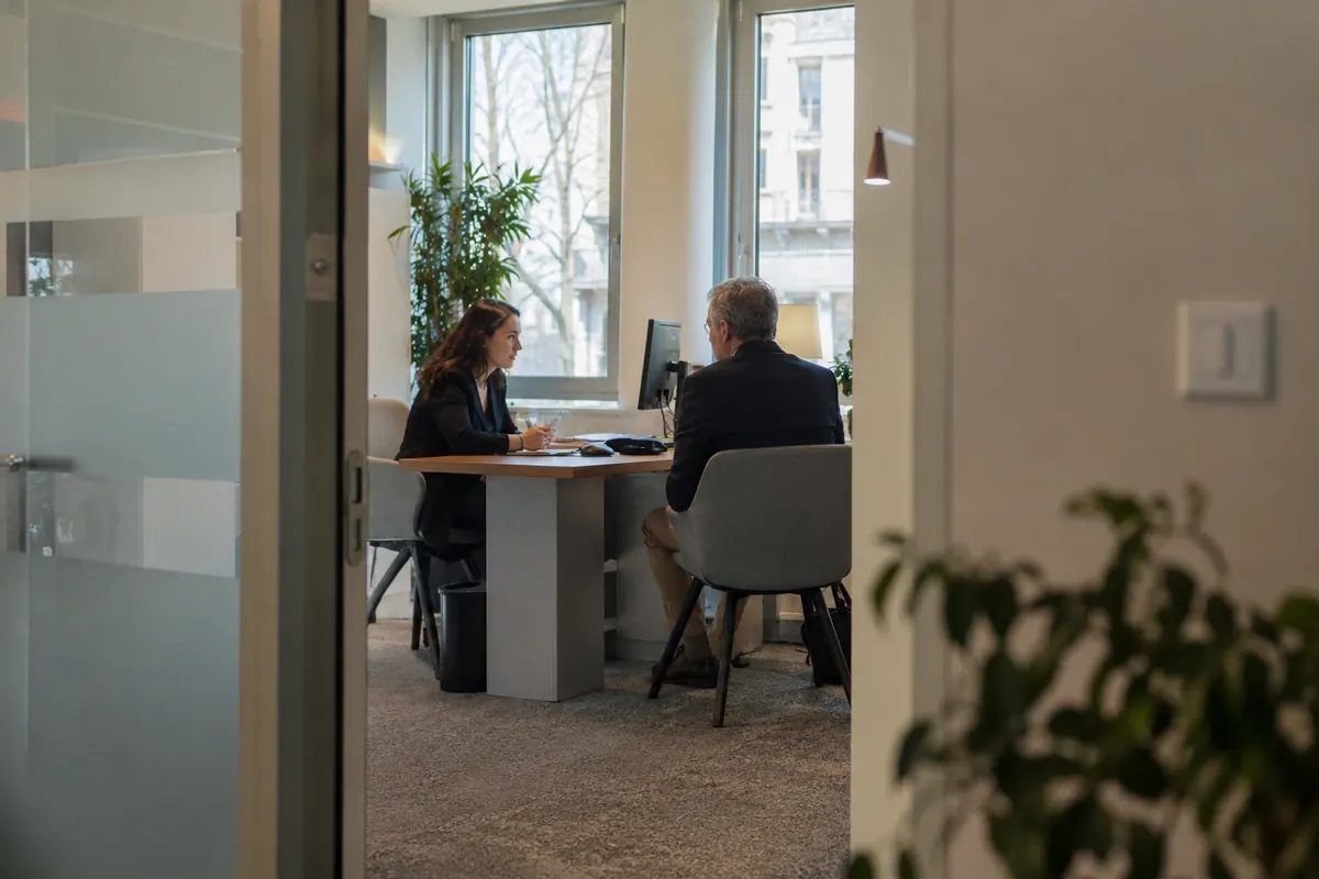 Entretien bancaire vu depuis le couloir — image d’ambiance générée par IA