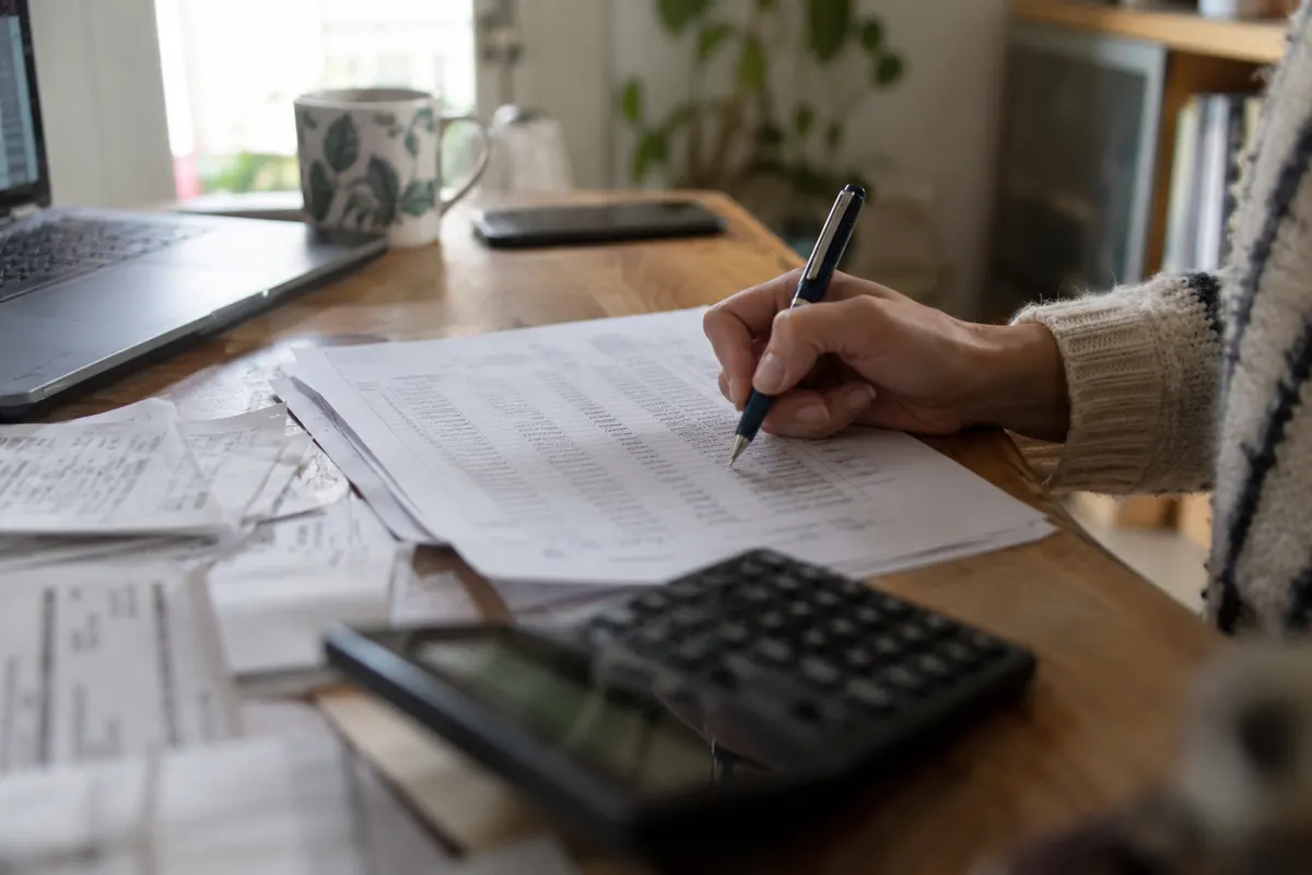 Main annotant des documents et calculatrice — image d’ambiance générée par IA